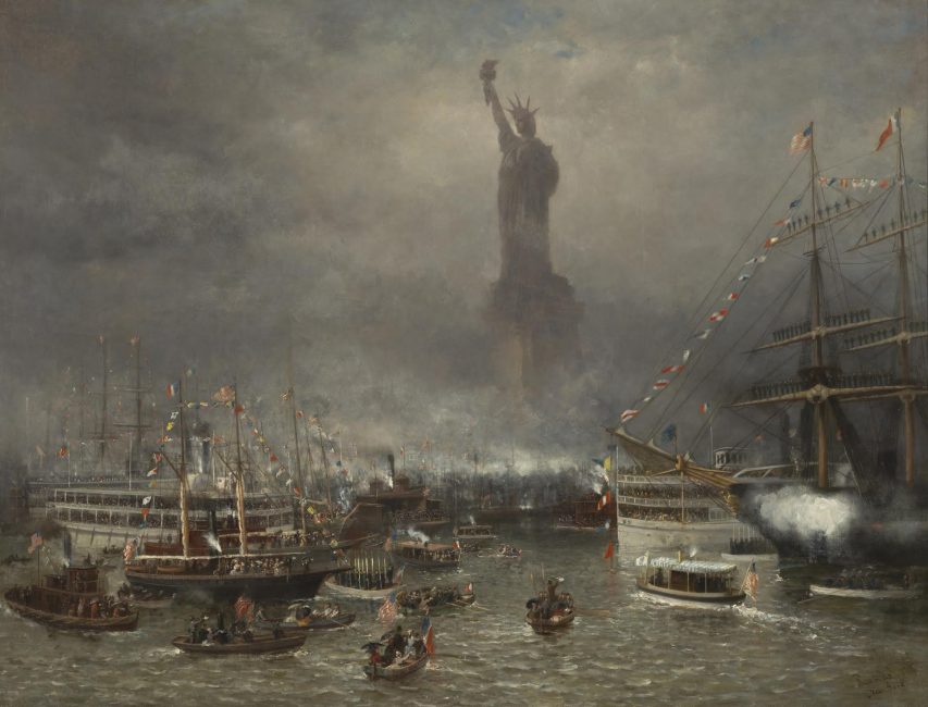 A group of onlookers gather to witness the unveiling of the Statue of Liberty in the New York Harbor. The Statue of Liberty stands triumphantly in the center of the picture with boats surrounding them on a gray day.